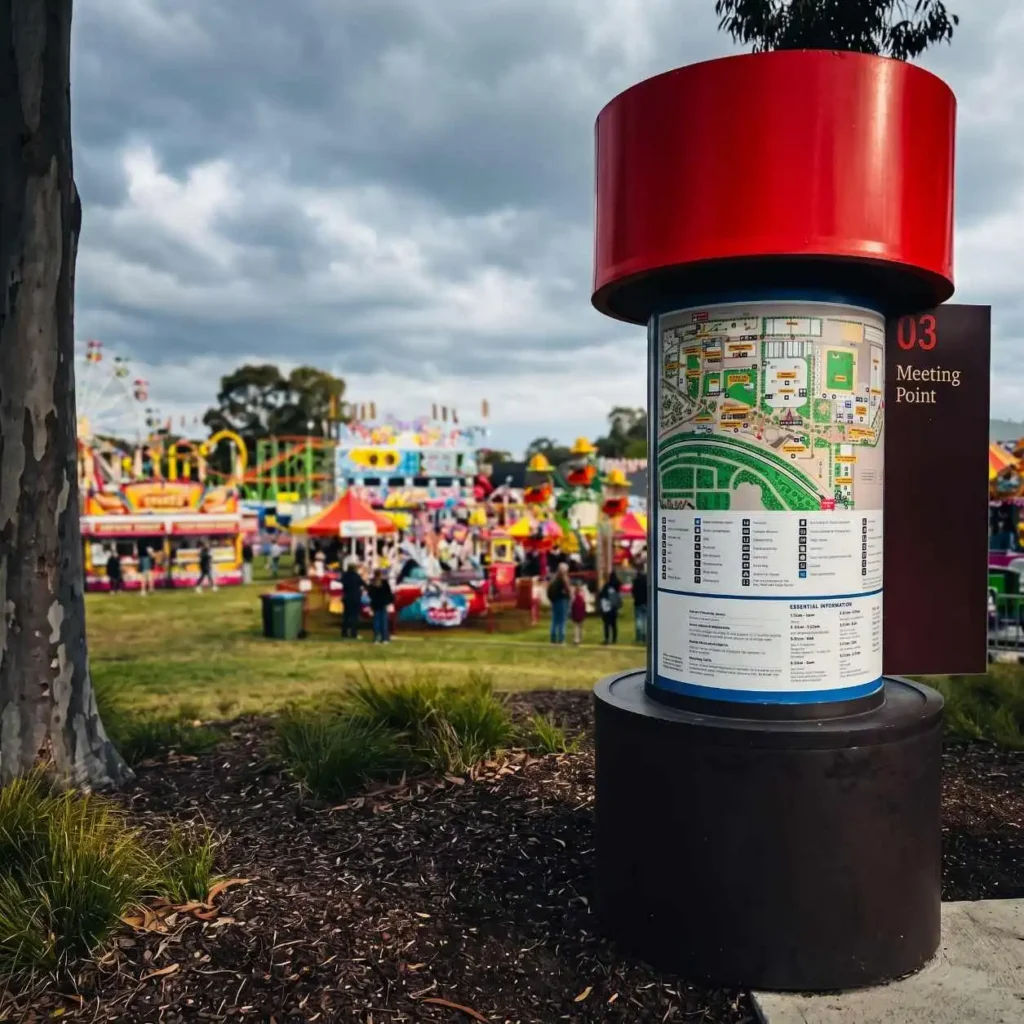 Why Mobiddiction builds Mapping Platforms | Mobiddiction Map kiosk with a bright red cylindrical top at a festival; sign reads '03 Meeting Point' beside a detailed map.